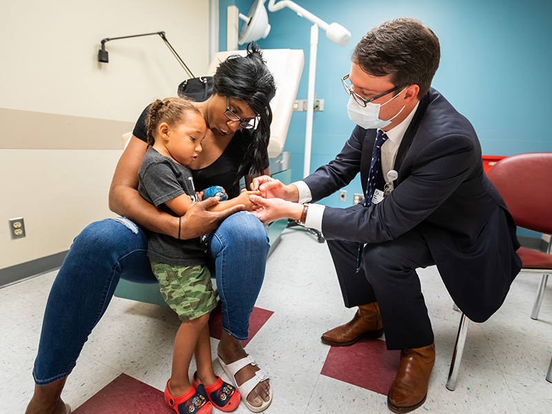 Chantel Strahan holds son Xavier as Dr. Marc Walker looks at his hand post-surgery in June.